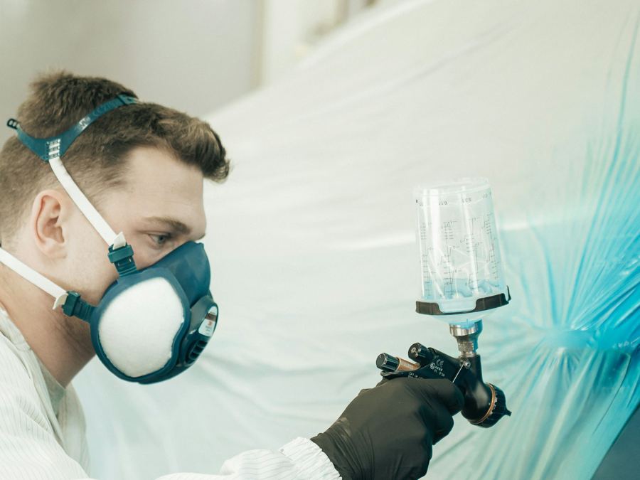 Painter spraying a car in the paint booth